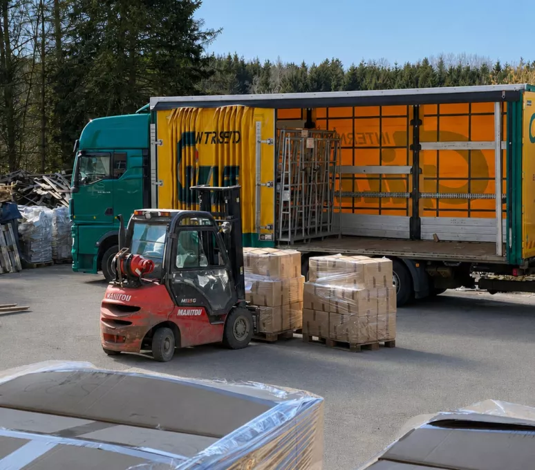 Gabelstapler verlädt folierte Paletten mit Restposten-Kartons auf einen LKW im Hof von Liquidato – Abholung und Export