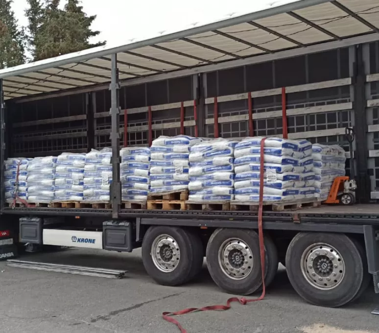 Lkw mit geöffneter Plane, beladen mit palettierten Baustoff-Säcken – Baumaterialien als B-Ware zum Ankauf