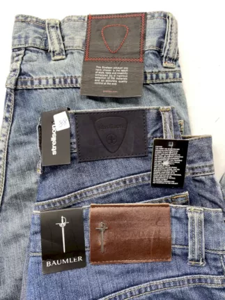 Nahaufnahme gestapelter Marken-Jeans von Strellson und Bäumler mit Lederpatches und Original-Anhängern