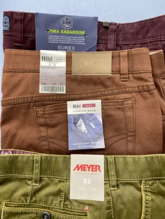 Gestapelte Marken-Hosen in Bordeaux, Braun und Oliv mit Etiketten von Eurex by Brax, Hiltl und Meyer