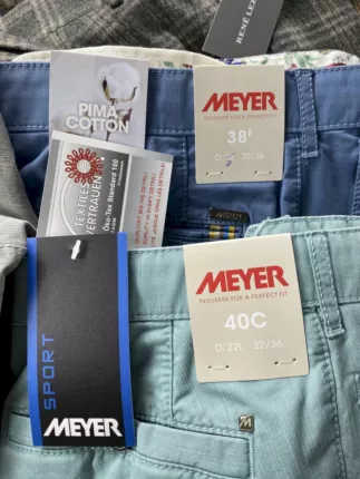 Blaue und mintgrüne Meyer-Hosen mit Original-Etiketten sowie Pima-Cotton- und Öko-Tex-Anhängern