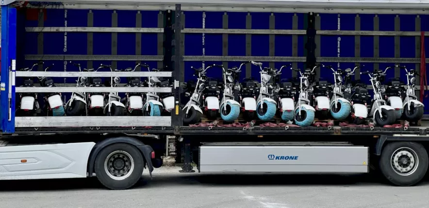 Elektroscooter-Ladung mit Spanngurten im offenen Lkw