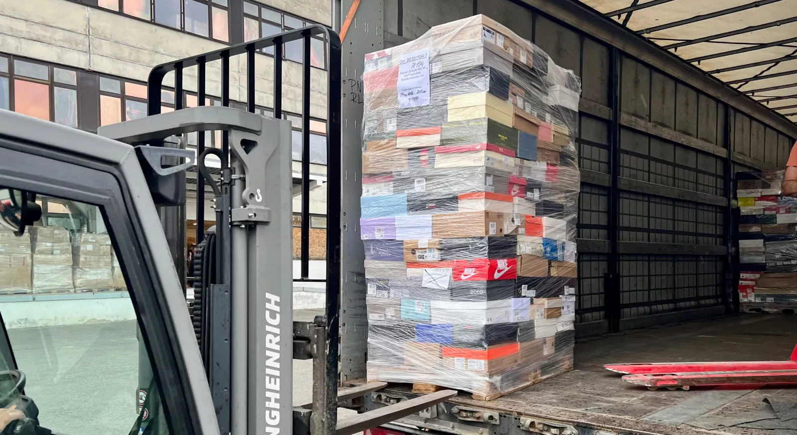 Restposten-Palette mit Markenschuhen von Nike und Adidas wird im Liquidato-Lager für den Export verladen