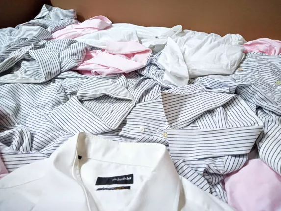 Berufsbekleidung als Kiloware: lose Business-Hemden in Weiß, Rosa und mit Nadelstreifen im Warenkarton