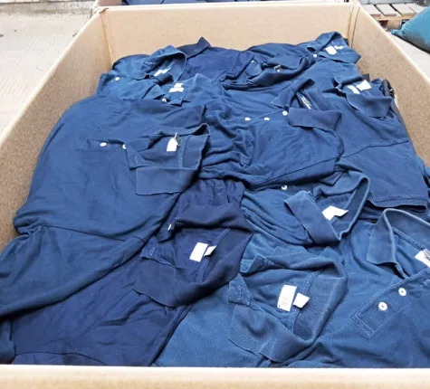 Große Menge dunkelblauer Poloshirts als lose Kiloware in einem Warenkarton