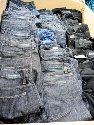 Gefaltete dunkle Jeans und schwarze Business-Hosen, gestapelt in einem Karton