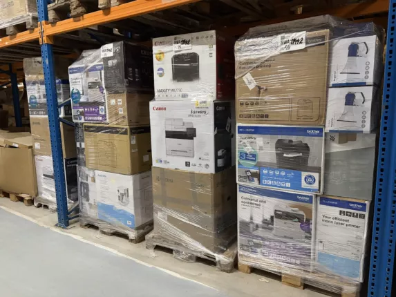Gestapelte Paletten mit originalverpackten Büro-Multifunktions- und Laserdruckern im Palettenregal eines Großhandelslagers