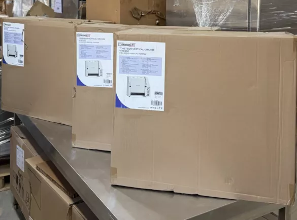 Originalverpackte Profi-Gastro-Toaster, gestapelt auf einem Edelstahl-Arbeitstisch im Lager