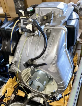 Detail eines Stromerzeuger-Motors mit Aluminiumgehäuse, Zündspule und Schutzkontakt-Steckdose