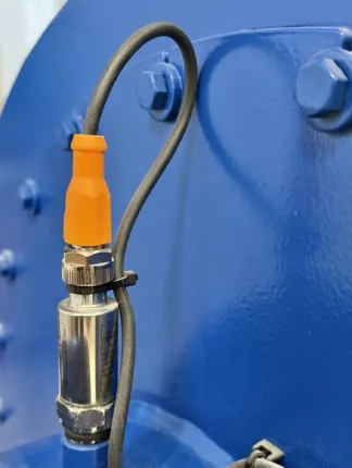 Vibrations- und Temperatursensor mit orangefarbenem Steckverbinder am Gehäuse des Zentrifugalventilators – Detailaufnahme