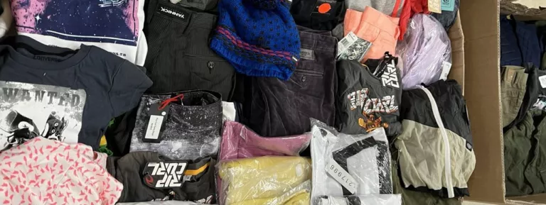 Textil-Restposten: sortierte Kleidung und Textilien im Karton